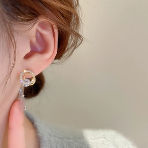 Close-up of elegant gold geometric circle earrings with zircon stones on a model