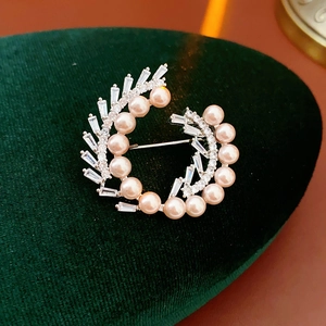 Macro shot of silver wreath brooch with pearls and cubic zirconia on green velvet