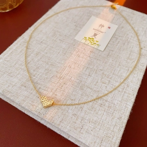 Detailed macro view of gold heart pendant with retro hammered metal texture and slim chain