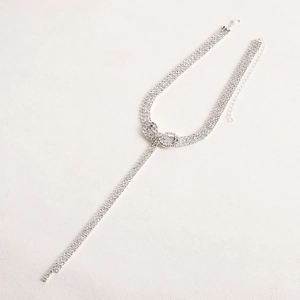 Macro detail of silver bow choker necklace with sparkling rhinestones and long tassels