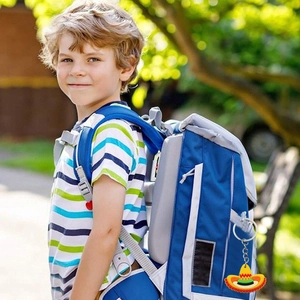 Mexican sombrero keychain hanging on a blue backpack in a natural outdoor park setting