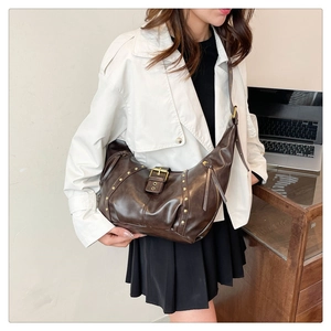 Detail of vintage dark brown faux leather crescent bag with golden rivets and strap buckles
