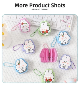 Detail of cute rabbit mini notebooks with ball chains shown next to a white keyboard