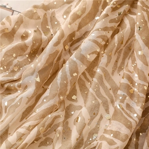 Detail view of beige scarf featuring golden foil zebra print and delicate fabric texture