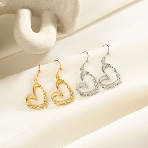 Gros plan de boucles d'oreilles cœur dorées et argentées avec strass sur soie blanche
