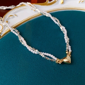 Detail of double-layer necklace with white pearls, silver beads and gold magnetic heart