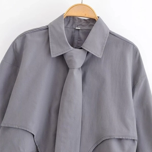 Dark grey long sleeve shirt with tie on wooden hanger against white background