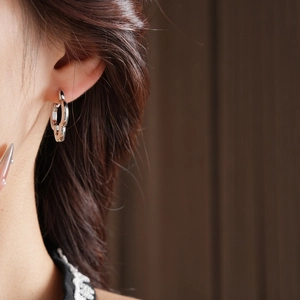 Detailed close-up of silver hollow clover chain earrings worn by a model in a luxury style