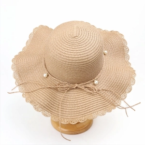 Detailed view of women's straw sun hat with pearl accents and wavy lace brim design