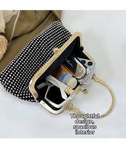 Detail view of black rhinestone evening bag with gold handle and spacious inner compartment