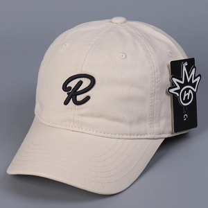 Primer plano del bordado letra R negra en gorra de algodón crema con etiqueta de marca