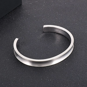 Macro detail of silver stainless steel cuff bracelet with grooved concave design