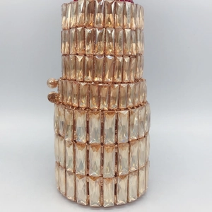 Detailed close-up of champagne crystal rhinestones on a cylindrical evening clutch bag