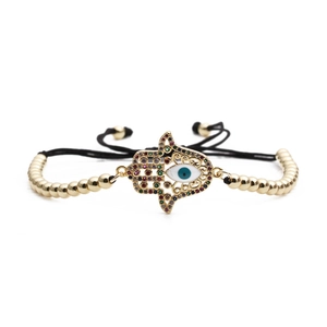 Goldenes Hamsa-Armband mit bösem Blick, Perlen und verstellbarer Kordel auf weißem Grund