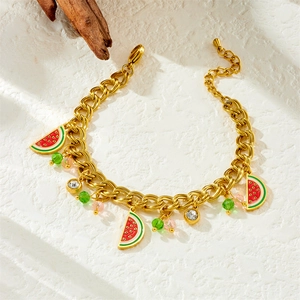 Golden bracelet with colorful enamel fruit charms and pearls on a white texture