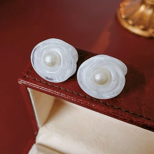 Detailed close-up of vintage flower pearl earrings on a burgundy leather jewelry box edge