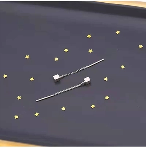 Silver drop earrings with fine chains and square pendants over a starry dark background