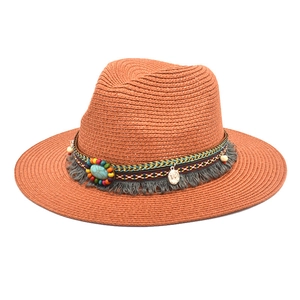 Detail of a brick red straw fedora featuring ethnic beads and a turquoise tassel band