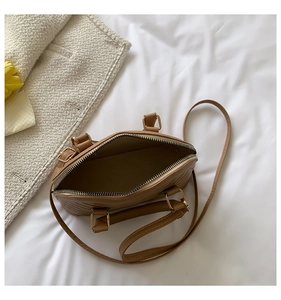 Top view of brown faux leather shell bag with diagonal stitching and open zipper detail