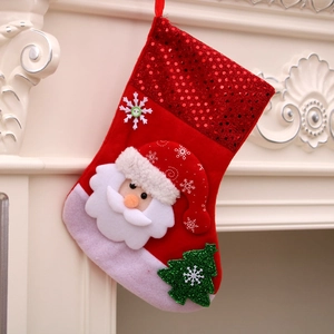 Festive red sequin Christmas stocking with Santa and tree decor hanging on fireplace