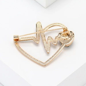 Close-up of golden heart-shaped brooch back with pulse lines and secure pin clasp