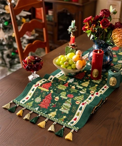 Close-up of green Christmas table runner with tassels and festive tree patterns