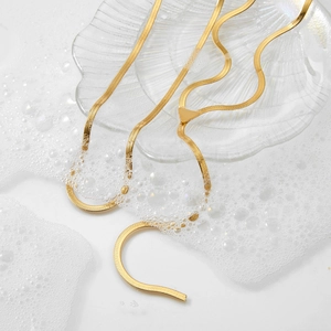 Zweilagige goldene Edelstahl Y-Halskette auf einer Glasschale mit weißen Seifenblasen
