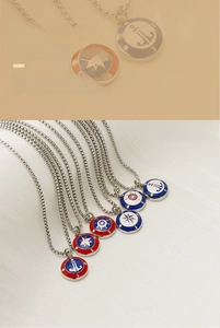 Detail of red and blue enamel nautical compass and anchor pendants on stainless steel chains