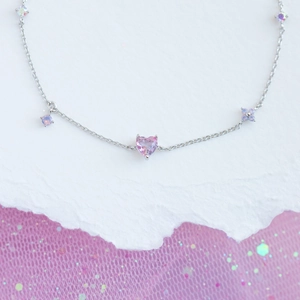 Macro shot of silver chain bracelet with pink heart and purple flower charms