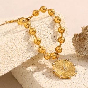 Dettaglio del bracciale di perle dorate con ciondolo a stella su pietra testurizzata