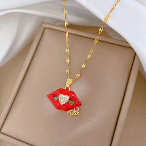 Detail of gold chain necklace with red lip pendant featuring zircon heart and kiss charm