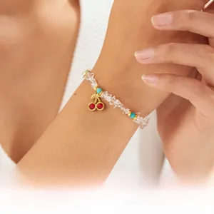 Detail of beaded bracelet featuring white turquoise and red cherry charm on model wrist