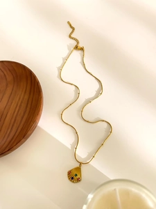 Detailed view of a gold shell pendant necklace with colorful gems on a beaded chain