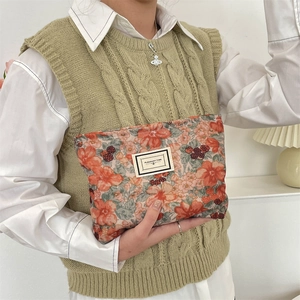 Macro shot of corduroy floral makeup bag with Pleasant Time label held by a hand