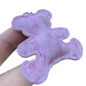 Pink PU leather bear keychain with ostrich texture and stitching on white background
