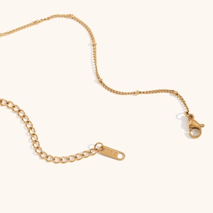 Detail of 18K gold plated necklace with lobster clasp and engraved metal tag