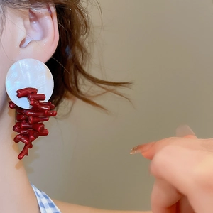 Close-up of red and white resin drop earrings worn by a model in a modern style