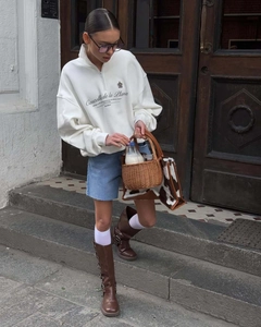 Street style view of white half-zip sweatshirt paired with denim shorts and boots