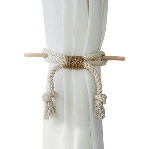 Nordic woven cotton curtain tieback with wooden rod and tassel on a white curtain