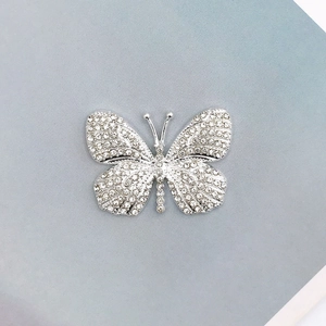 Macro detail of a silver butterfly charm fully inlaid with sparkling rhinestones