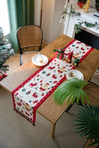Close-up of Christmas table runner with Santa motifs and festive red tassels on wood