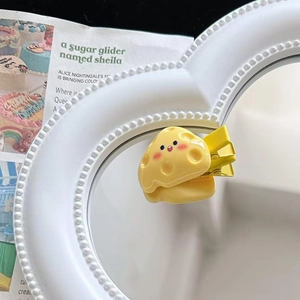 Close-up of yellow cartoon cheese hair clip with smiley face on a white mirror