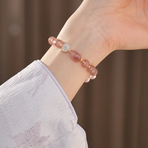 Detail of pink strawberry crystal beads with a white jade平安扣 and gold accents on wrist