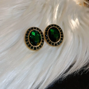 Gros plan de boucles d'oreilles émeraude ovales avec halo de cristaux sur fourrure