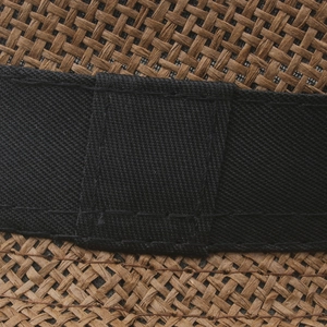Detail of dark brown straw sun hat with black ribbon and dense woven fiber texture