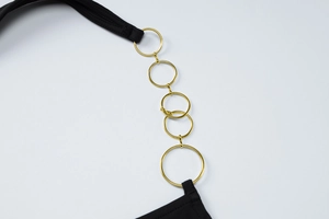 Détail de la bretelle noire avec cinq anneaux en métal doré pour un look élégant et chic