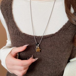 Close-up of star-shaped tiger eye stone pendant on a silver beaded necklace chain