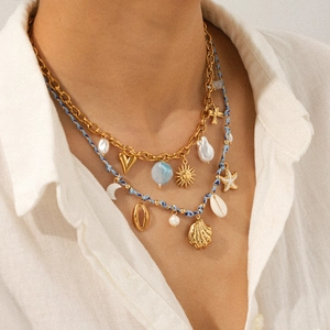 Close-up of double-layer necklace with 18k gold chain, blue beads, and coastal charms