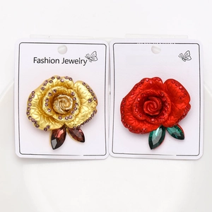 Detailed macro view of enamel rose brooches in gold and red with sparkling rhinestones