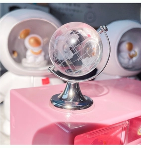 Macro shot of transparent crystal mini globe with silver metal base on a pink desk surface